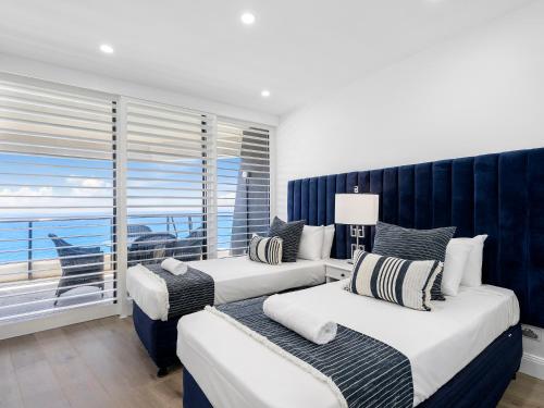 two beds in a room with a view of the ocean at Oracle Resort Broadbeach - gclr in Gold Coast