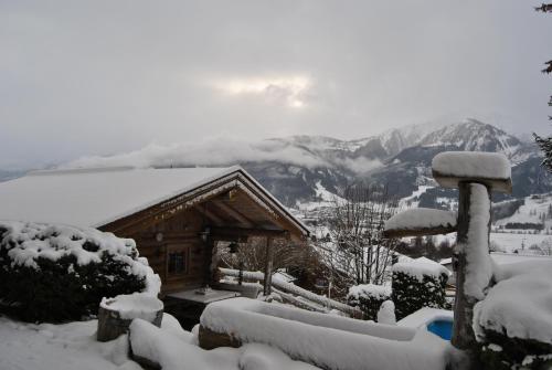 a cabin covered in snow with mountains in the background at Landhaus Kitzblick in Piesendorf