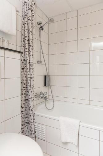 a white bathroom with a shower and a tub at Thon Partner Hotel Backlund in Levanger