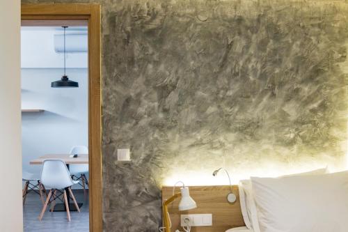 ein Schlafzimmer mit einer Steinmauer, einem Bett und einem Tisch in der Unterkunft Remis Studios in Rethymno