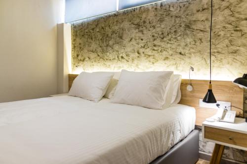 a bedroom with a white bed with a stone wall at Remis Studios in Rethymno Town