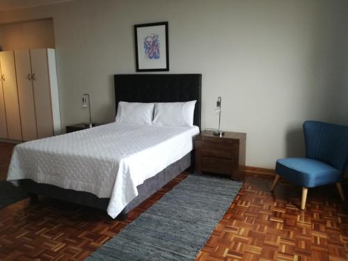 1 dormitorio con 1 cama y 1 silla azul en Durban Penthouse, en Durban
