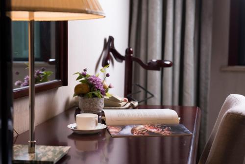 a table with a lamp a book and a cup of coffee at Zhejiang Xizi Hotel in Hangzhou