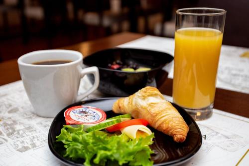 a plate of food and a cup of orange juice at Hotel Vanha Rauma in Rauma