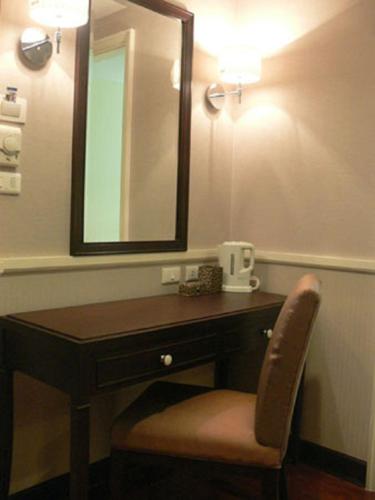 a bathroom with a vanity with a mirror and a chair at Aurum The River Place in Bangkok