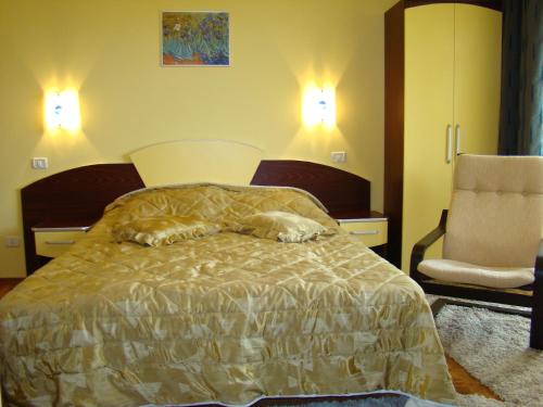 a bedroom with a bed with two pillows and a chair at Complex Turistic Le Baron in Vatra Dornei