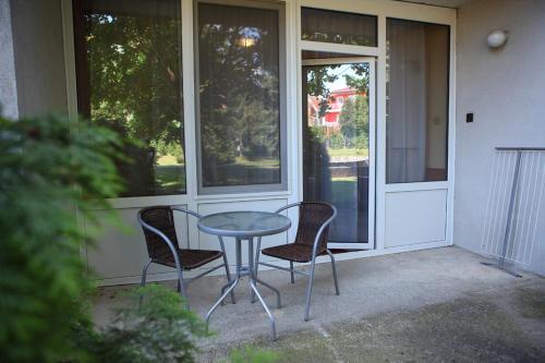 a glass table and two chairs on a patio at Hotel Napsugar in Hévíz