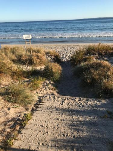 a sign on a beach with the ocean in the background at Bar Harbor in Papamoa