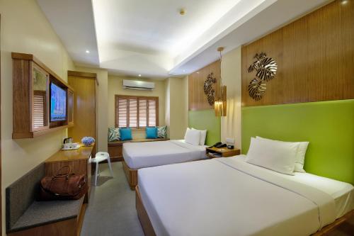 a hotel room with two beds and a television at BE Resort Mactan in Mactan