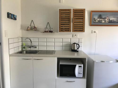 a kitchen with a sink and a microwave at Bar Harbor in Papamoa