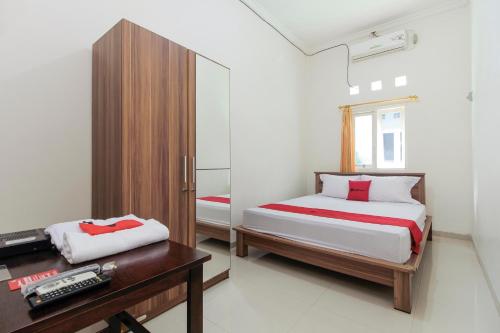a bedroom with two beds and a desk and a mirror at RedDoorz near Universitas Palangkaraya in Palangkaraya