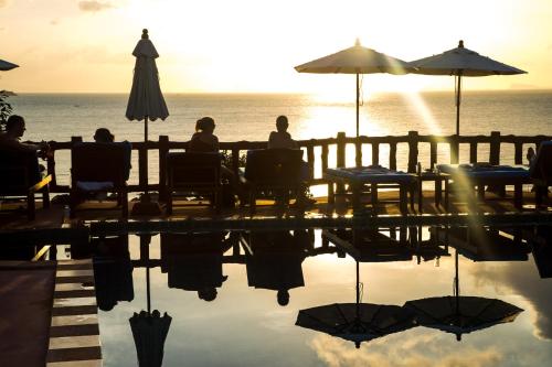 a group of people sitting at a table near the ocean at Zama Resort Koh Phangan in Haad Chao Phao