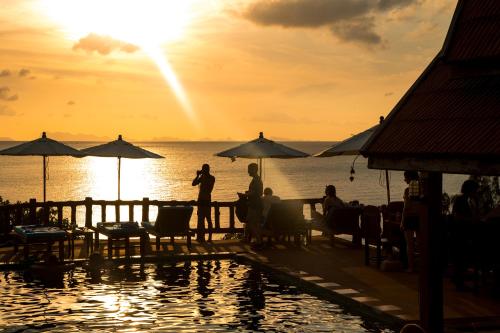 a group of people sitting on a dock near the water at Zama Resort Koh Phangan in Haad Chao Phao