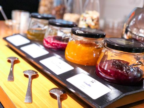 a group of jars of jam on a table with spoons at IMPULSIV Hotel & Sportresort in Lörrach