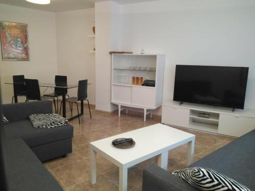 a living room with a couch and a tv and a table at Apartamento nuevo en Vilafamés in Vilafames