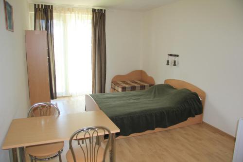 a small bedroom with a bed and a table and chairs at Aulaukio Baltija in Pape