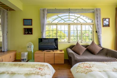 sala de estar con 2 camas, sofá y ventana en Yunnan Homestaty, en Renai
