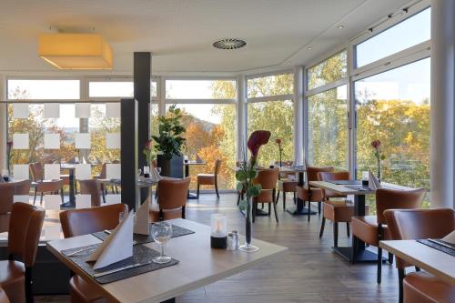 un restaurante con mesas, sillas y ventanas en Parkhotel CUP VITALIS en Bad Kissingen