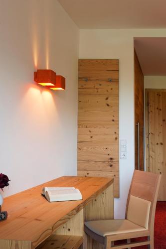 a wooden desk with a book and a lamp at Hotel Flatscher in Stuhlfelden