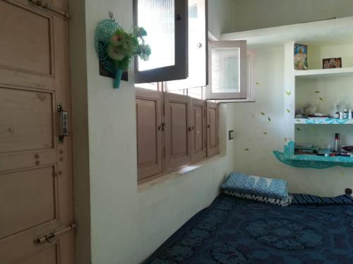 Zimmer mit weißen Wänden, einem Fenster und einem blauen Teppich in der Unterkunft ANBU RAMANA Guest House in Tiruvannāmalai