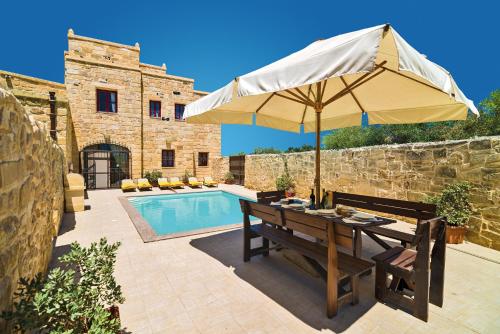 einen Tisch mit einem Sonnenschirm neben einem Pool in der Unterkunft Villa Valletta in Żejtun