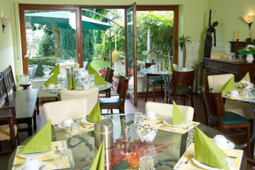 un restaurante con mesas y sillas con servilletas verdes en Art-Hotel Sonnenhof, en Hanau am Main