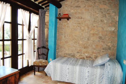 a bedroom with a bed and a stone wall at Cal Teulats - Masoveria in Perafita