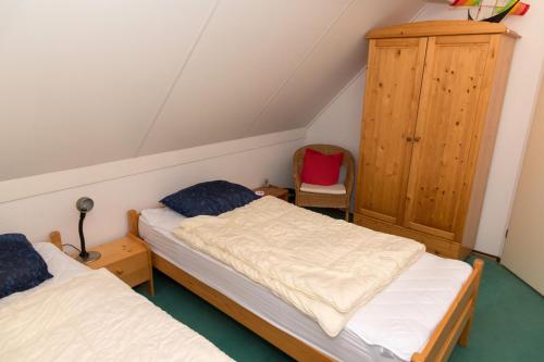 a attic room with two beds and a cabinet at Hello Zeeland - Vakantiehuis Zwin 174 in Breskens
