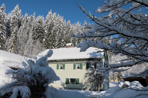 a house covered in snow with trees in the background at Ferienwohnung Saunahaus in Annaberg im Lammertal