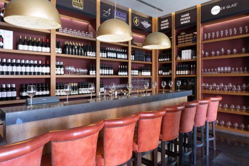 a bar with red leather chairs and wine bottles at Cramim by Isrotel Exclusive in Qiryat ‘Anavim