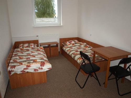 Habitación con 2 camas, escritorio, mesa y sillas. en Hostel Hutnik, en Ostrowiec Świętokrzyski
