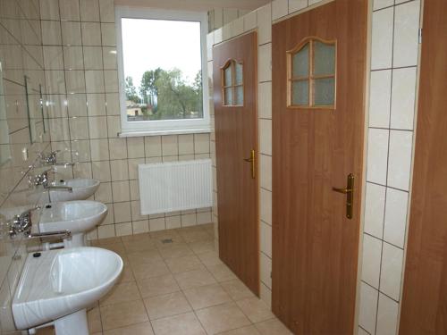 a bathroom with two sinks and a door with a window at Hostel Hutnik in Ostrowiec Świętokrzyski