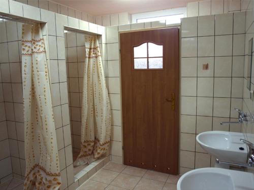 a bathroom with a shower and a sink and a door at Hostel Hutnik in Ostrowiec Świętokrzyski