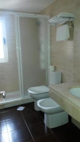 Baño blanco con aseo y lavamanos en Hotel Casa Fernando II, en Rellayo