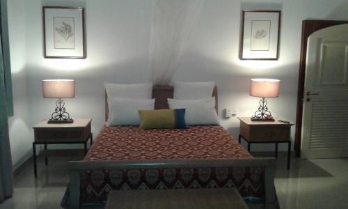a bedroom with a bed with two lamps on two tables at Shanti Nivas in Post of Flacq
