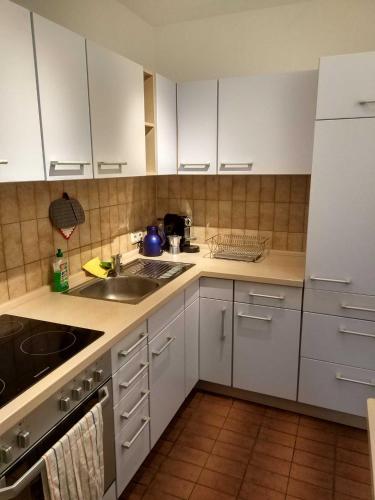 a kitchen with white cabinets and a sink at Sonnige EG_Wohnung mit Garten Terr in Forchheim