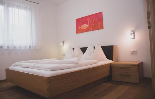 ein großes Bett mit weißer Bettwäsche und Kissen darauf in der Unterkunft Appartment Waldrand in Kastelruth