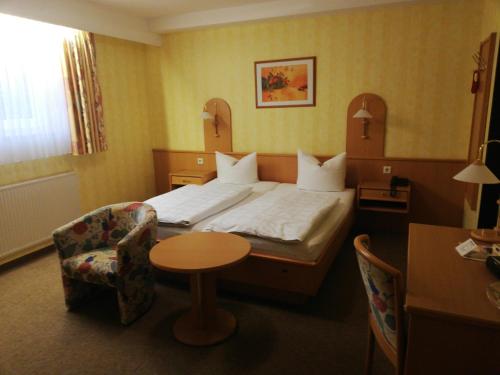 a hotel room with a bed and a table and a chair at Hotel Alex Herbermann in Glandorf