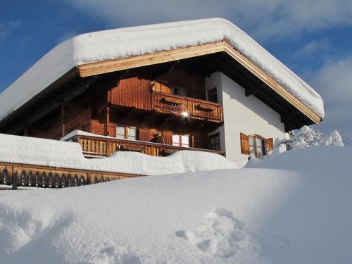 ein schneebedecktes Gebäude mit einem Stapel Schnee in der Unterkunft Gästehaus Bergstüberl in Reit im Winkl