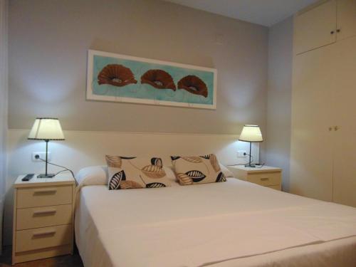 ein Schlafzimmer mit einem weißen Bett und zwei Lampen in der Unterkunft Apartaments Voramar in Cambrils