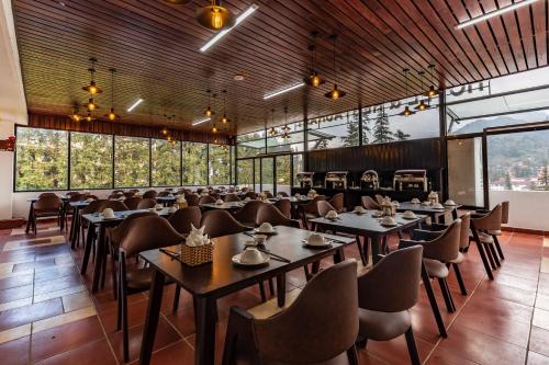 comedor con mesas y sillas y ventanas grandes en Sapa Melody Hotel, en Sa Pa
