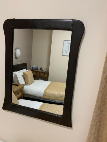 a mirror on a wall with a bed in a room at Royal Hotel in Dingwall