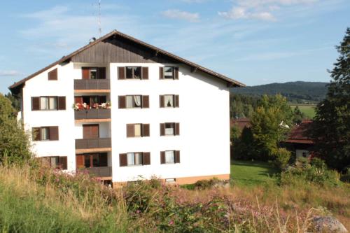 a white building with a balcony on a hill at Fewo mit malerischem Bergblick im in Bischofsmais