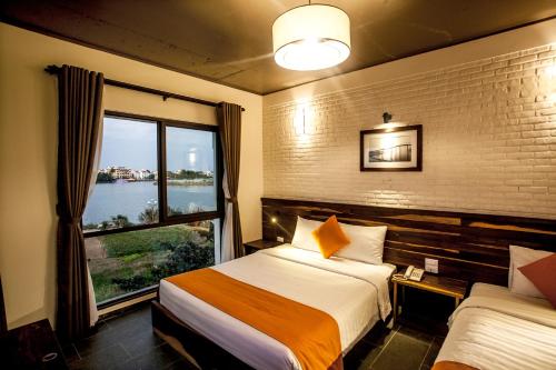 Cette chambre comprend 2 lits et une fenêtre. dans l'établissement Sông Lụa (Silk River Villa), à Hội An