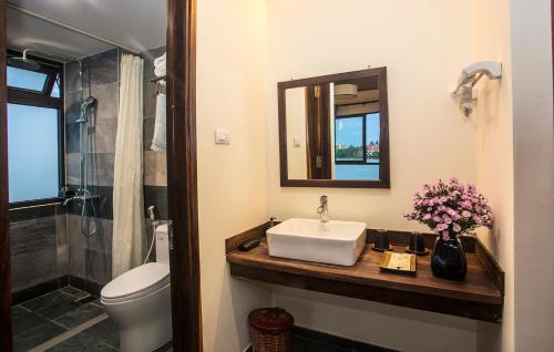 La salle de bains est pourvue d'un lavabo, de toilettes et d'un miroir. dans l'établissement Sông Lụa (Silk River Villa), à Hội An