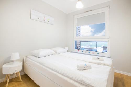 a bedroom with a white bed and a window at Apartments Gdynia Na Fali with Parking by Renters in Gdynia