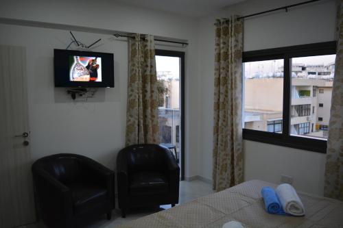 a bedroom with a bed and a tv and a chair at P.L Hermes Studios & Apartments in Larnaka