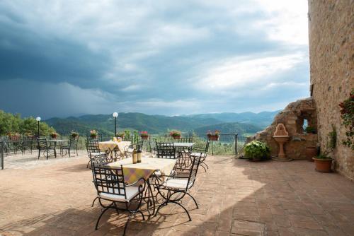 a patio with tables and chairs with mountains in the background at Il Castello Di Perchia in Crocemaroggia