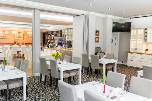 un restaurant avec des tables et des chaises blanches et un bar dans l'établissement Hotel Europejski, à Nysa