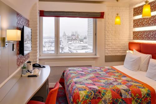 a hotel room with a bed and a desk and a window at Vega Izmailovo Hotel in Moscow